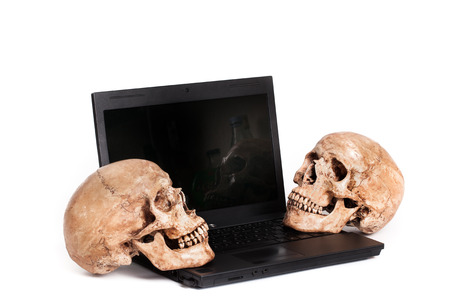Two human skulls placed on laptop isolated white backgroundの写真素材