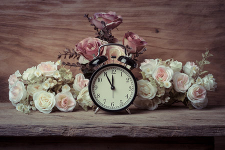 vintage alarm clock with flowers on wooden tableの写真素材