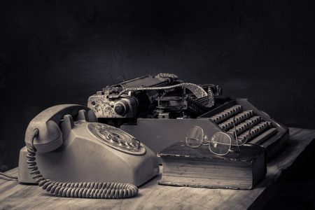 still life with old typewriter, telephone and glasses on old bookの写真素材