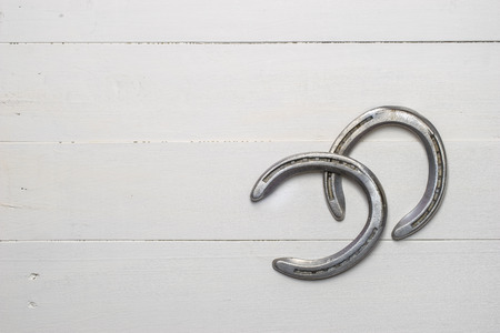Old cast iron metal horse shoeing accessory on white wood plank backgroundの写真素材