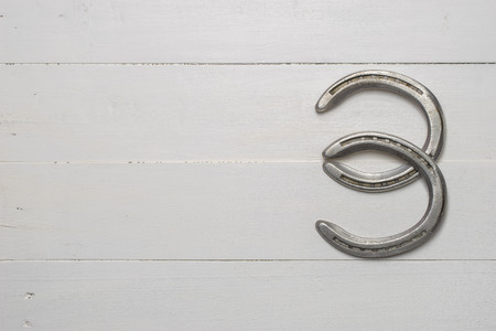 Old cast iron metal horse shoeing accessory on white wood plank backgroundの写真素材