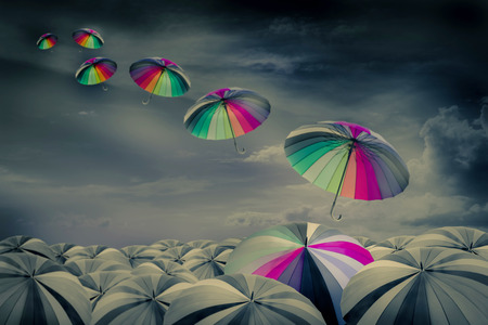rainbow umbrella in the mass of black umbrellasの写真素材