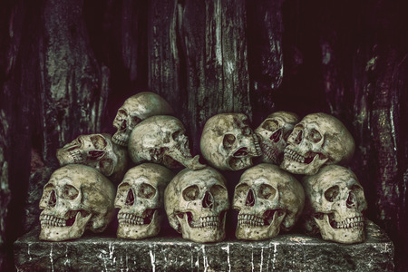 Stack of human skulls on stone table for sacrifice with golden and candle waxの写真素材