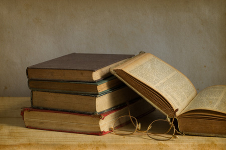 old book open on a wooden table with glassesの写真素材
