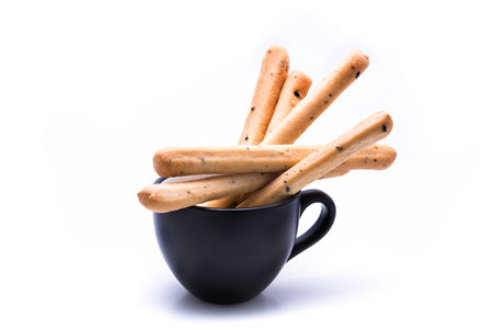 Bread sticks in black coffee cup isolated on white background with copyspace for text.