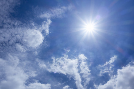 Strong sun in blue sky and white clouds