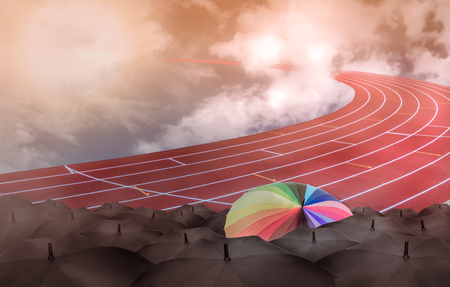 Rainbow umbrella in race field toward into sky with clouds, competition or leadership conceptの写真素材