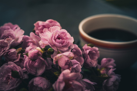 A cup of hot coffee and flowers. Romantic background with retro filter effectの写真素材