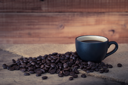 Coffee cup and coffee beans on old wooden backgroundの写真素材
