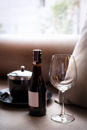 wine bottle, glass and ice bucket on sofa with window lightの写真素材