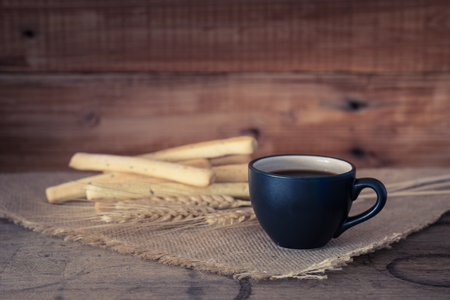 Coffee cup and breadsticks on old wooden backgroundの写真素材