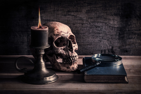 Vintage skull on antique book with candle and magnifying glassの写真素材