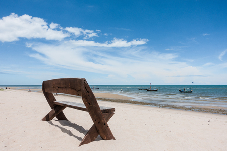 Wooden bench on white sand beach in sunny sky background, summer holiday conceptの写真素材