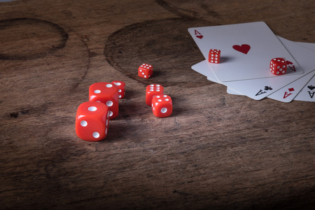 Lucky craps game dices and vintage poker cards with winning aces and gambler good luck charm on rustic wood table in western gambling saloonの写真素材