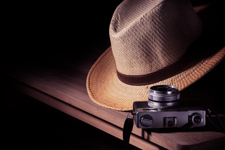 Old camera with hat on wooden table, still lift and vintage effectの写真素材