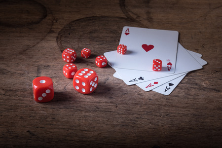 Lucky craps game dices and vintage poker cards with winning aces and gambler good luck charm on rustic wood table in western gambling saloonの写真素材