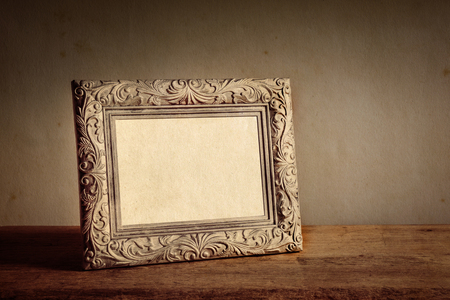 Vintage photo frame on wooden table over grunge backgroundの写真素材
