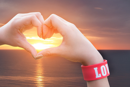 Female hands in form of heart on sunrise backgroundの写真素材