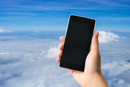 A man holding modern smart phone with blank screen in hand with sky backgroundの写真素材