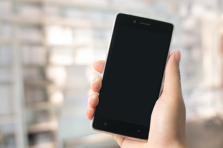 A man holding modern smart phone with blank screen in hand. Closeup shot. Concept for business onlineの写真素材