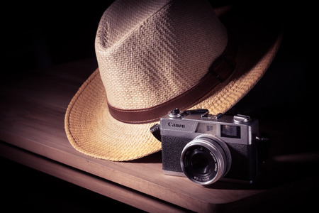 Old camera with hat on wooden table, still lift and vintage effectの写真素材