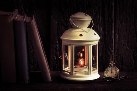 Vintage ole lantern with old books and retro pocket watch, on weatherd wood backgroundの写真素材