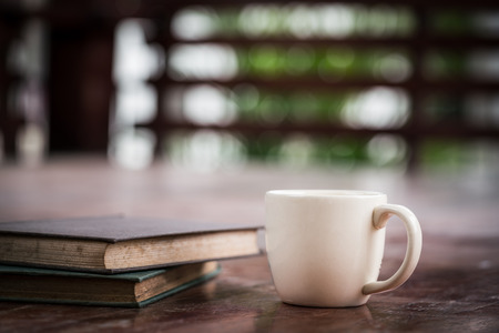 Hot coffee cup and old books on wooden tableの写真素材