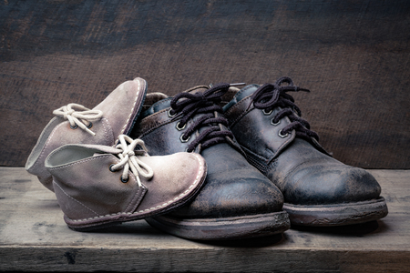 Brown shoes of daddy and son on on wooden table, bar or counter over brown wood wall background, fathers day conceptualの写真素材
