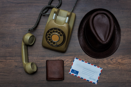 Top view communication tools with old dial phone,  wallet, leather hat, envelope on table wooden with copy space. travel and communication conceptの写真素材