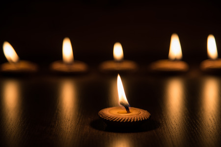 Candle light in clay pot on wooden background in the dark, selective focusの写真素材