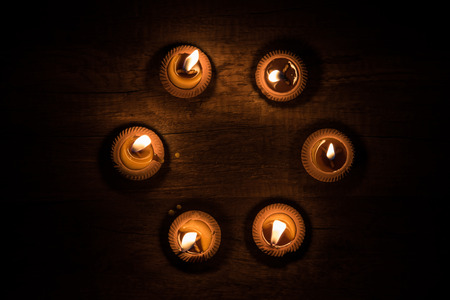 Candle light in clay pot on wooden background in the dark,の写真素材