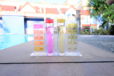 Laboratory test tubes with colorful liquid on the background of the swimming pool,swimming pool PH check test for water maintenance,pool water quality maintenance.の写真素材