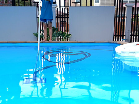 Woman cleaning swimming pool, water maintenance in the pool.