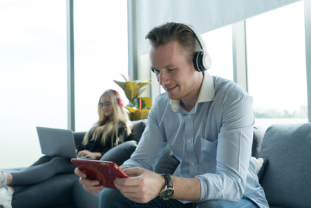 Yung couple in casual look enjoy social network and playing game from tablet stay together at home.