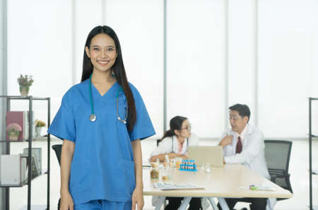 Smiling doctor stand in front of the medical team meeting at the background.の写真素材