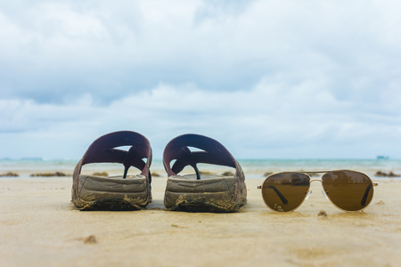 slippers and sunglasses on the beachの写真素材