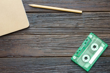 tape cassette, book and pencil on wooden background, musician equipment