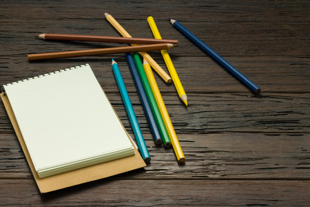 color pencil with note book on wooden table,copy spaceの写真素材