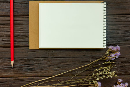 note book with red pencil and flower statice on wooden background, copy spaceの写真素材