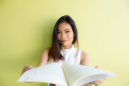 asian woman reading a book with green backgroundの写真素材