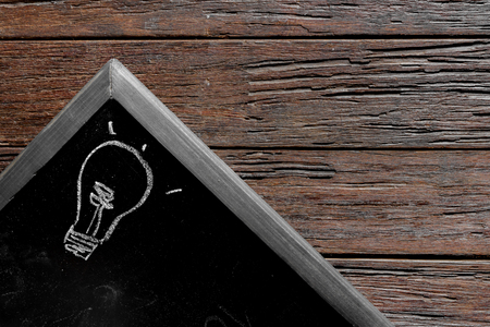 chalk and light bulb write on chalkboard on wooden table, idea conceptの写真素材
