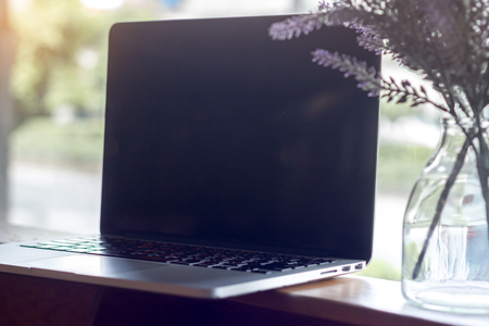 computer laptop on wooden table with window lightの写真素材