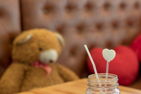glass with straw look alike white heart, on wooden table blur background, love conceptの写真素材