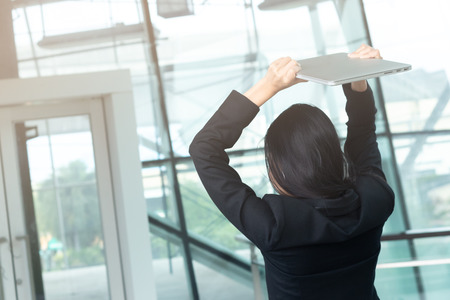 female office worker is angry and destroying laptop computerの写真素材