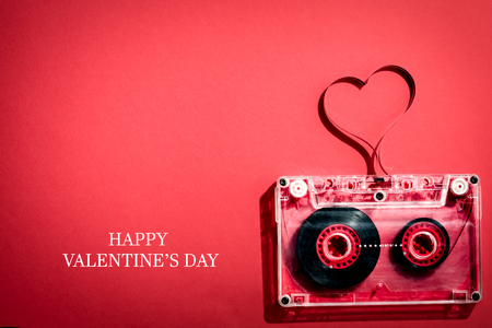 Valentines day card, audio cassette with magnetic tape in shape of heart on red backgroundの写真素材