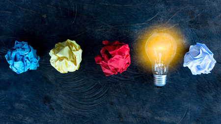 great idea concept with crumpled colorful paper and light bulb on wooden table	