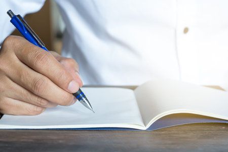 Man hand with pen writing on notebook.	