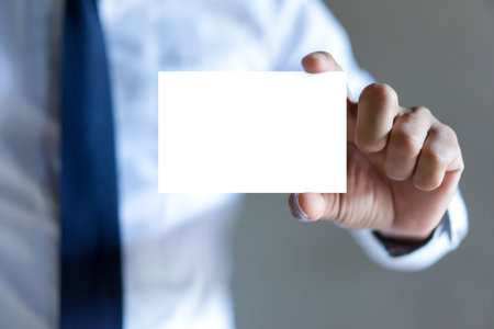 Man's hand showing business card - closeup shot on grey background