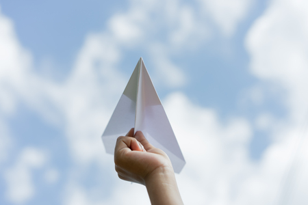 plane paper in children hand and blue sky in cloudy day. business concept.	の写真素材
