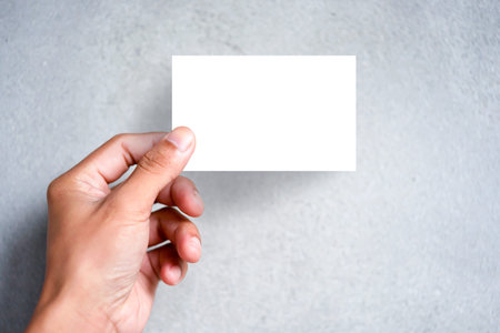 Hand holding blank plain white business card design mock up. Clear call id card mock up template hold arm. Visit pasteboard paper surface display front. Small pure offset name card print.Logo brandingの写真素材